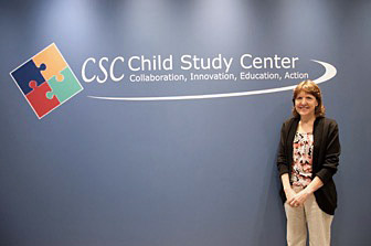 Karen Bierman standing by the CSC logo