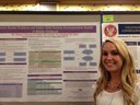 Photo of Meghan Casey standing next to a research poster