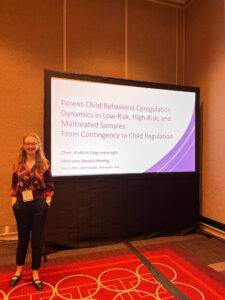 Kivilcim Degirmencioglu standing next to large screen displaying name of talk at 2025 SRCD