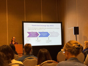 Kivilcim Degirmencioglu standing behind podium presenting at 2025 SRCD