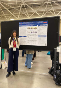 Lucia Herrero standing next to 2025 SRCD poster