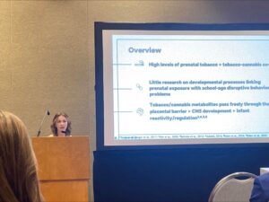 Madison Kelm standing behind podium presenting at 2025 SRCD
