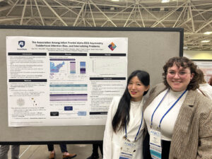 Sua Cho and Olivia Bell standing next to 2025 SRCD poster